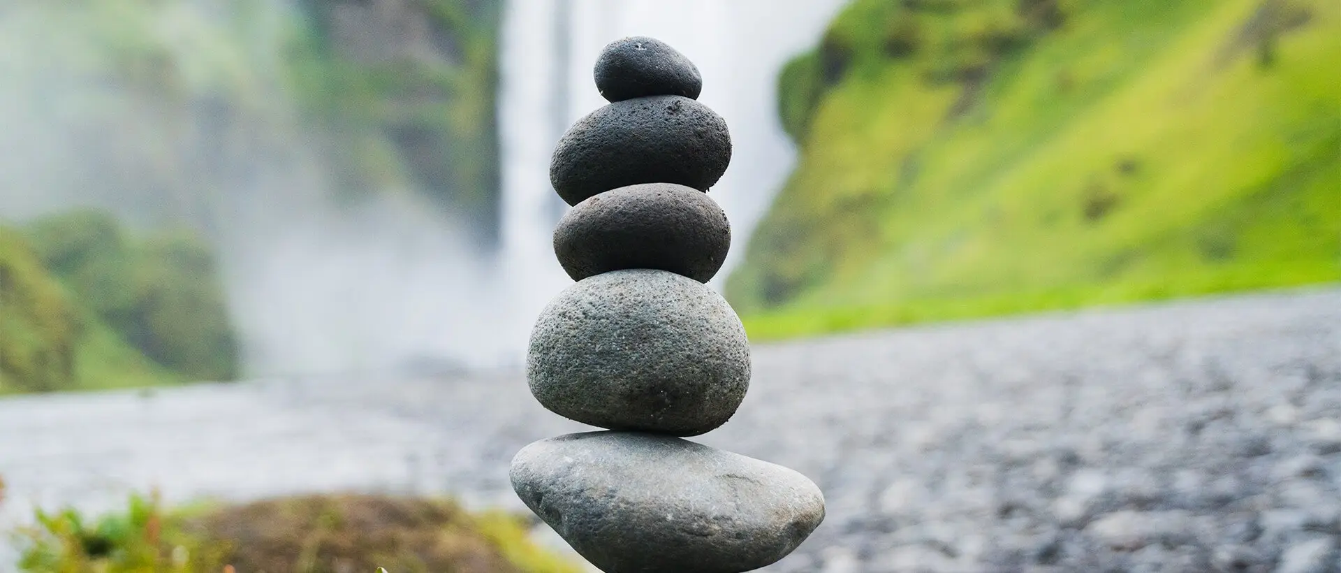 a stack of rocks sitting in front of a waterfall.