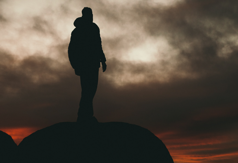 a silhouette of a person standing on top of a rock.