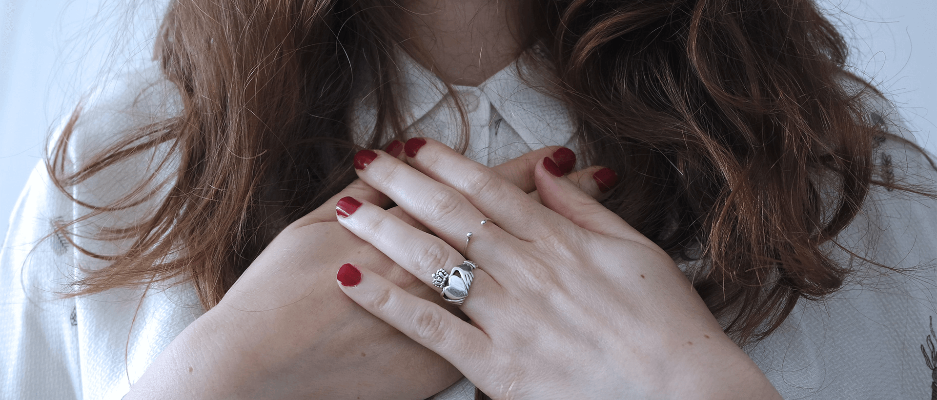 a woman with red nails and a ring on her hand.