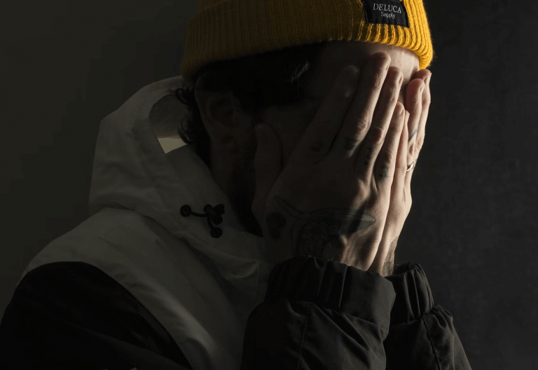 a man in a yellow hat covers his face with his hands.