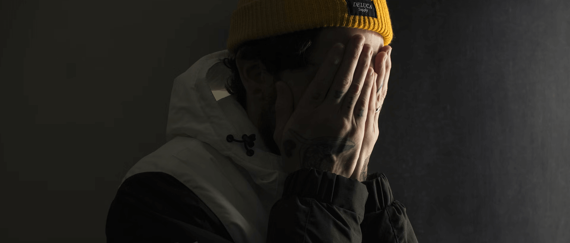 a man in a yellow hat covers his face with his hands.