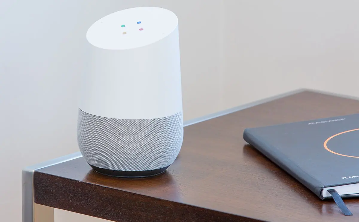 a google home sitting on a desk next to a laptop.