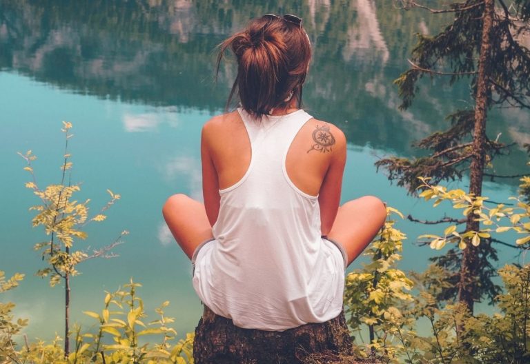 a woman sitting on a rock looking out over a lake.