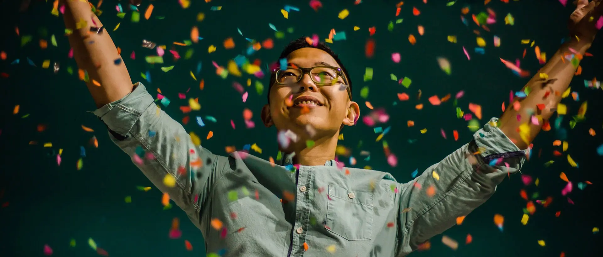 a man standing in front of confetti falling from his hands.