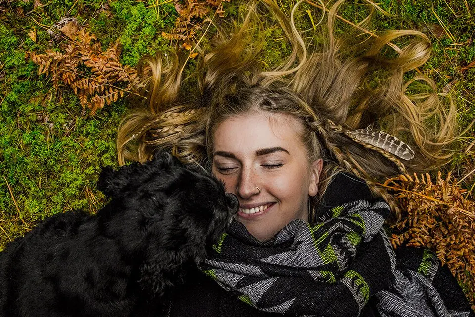 Woman laying on grass, happy with pet