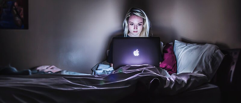 a woman sitting in bed using a laptop computer.