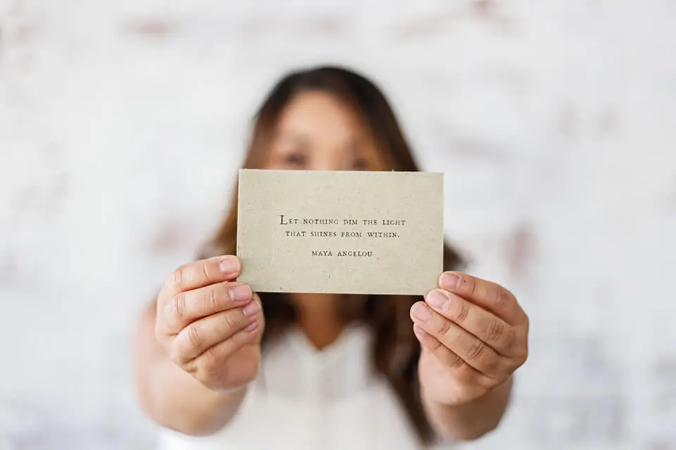 Woman holding up card with a Maya Angelou quote.