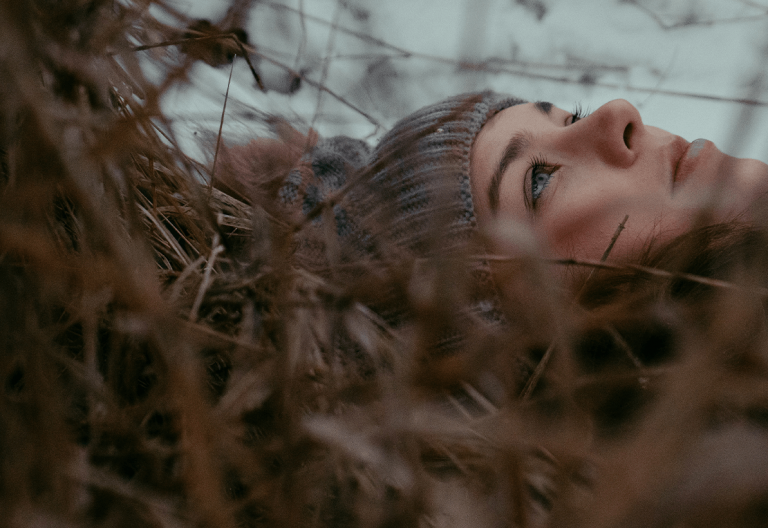 a woman laying down in a field of tall grass.