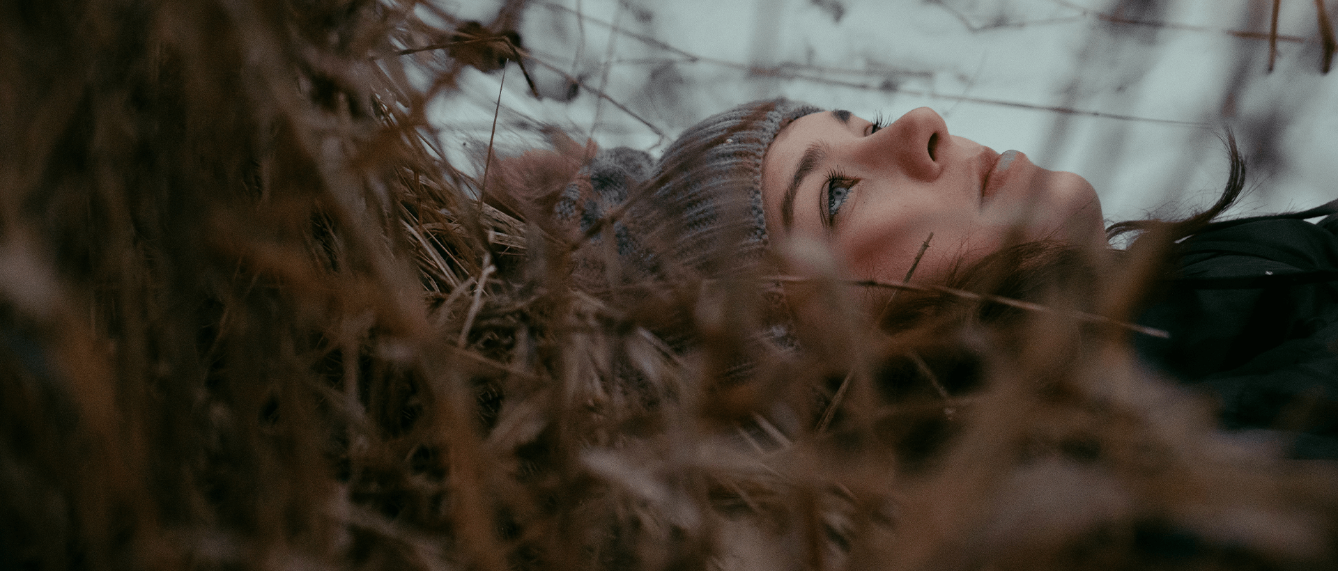 a woman laying down in a field of tall grass.