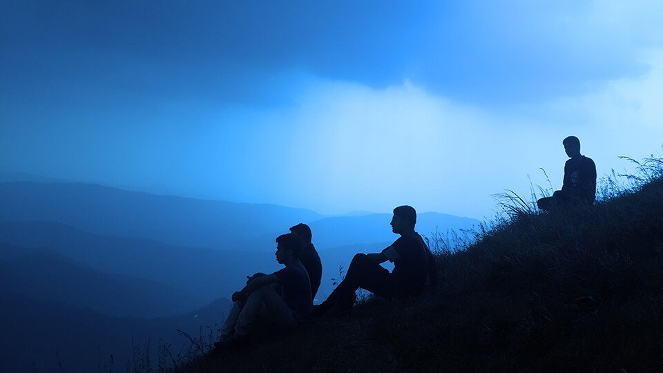 Group of friends on a high hill overlooking the clouds