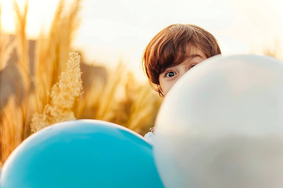 Boy in field, playing with balloons