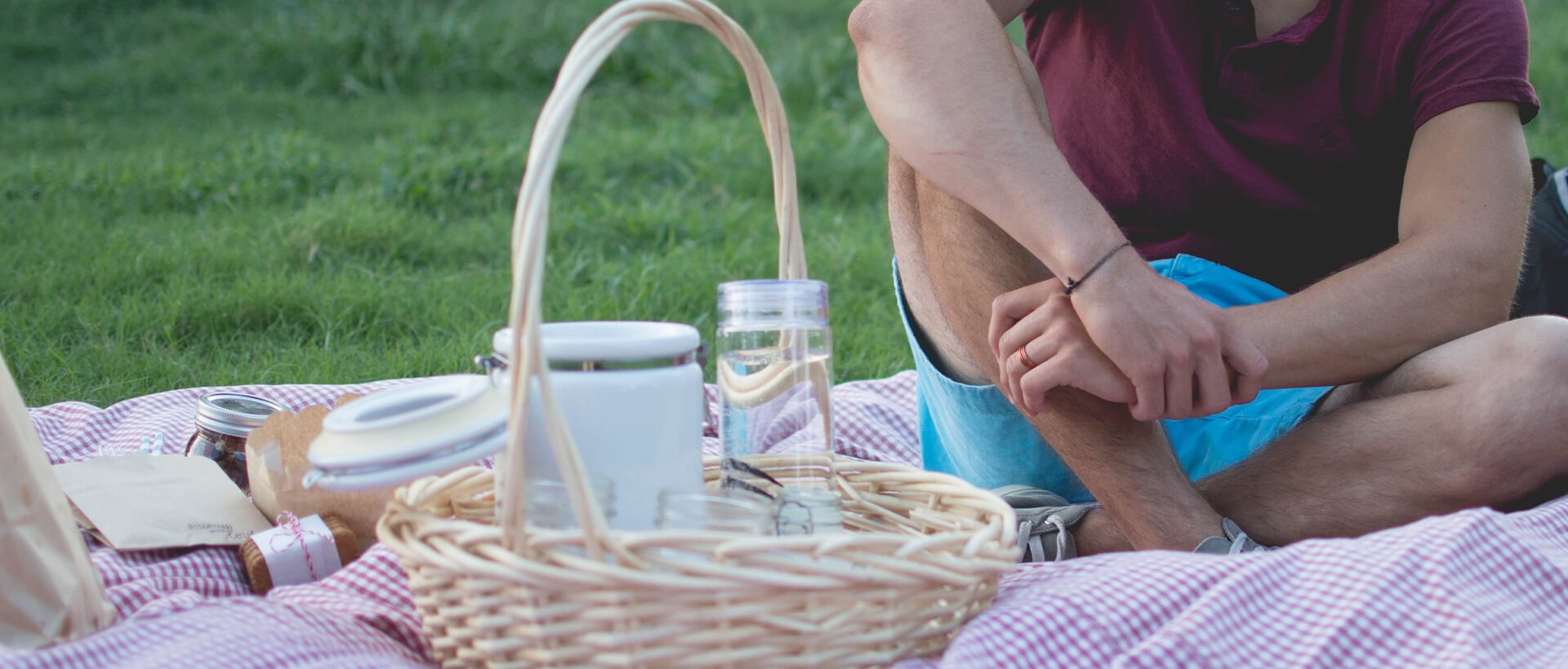 a man sitting on a blanket next to a picnic basket.