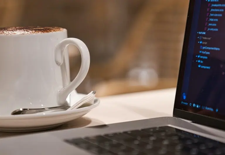 a cup of coffee sitting next to a laptop computer.