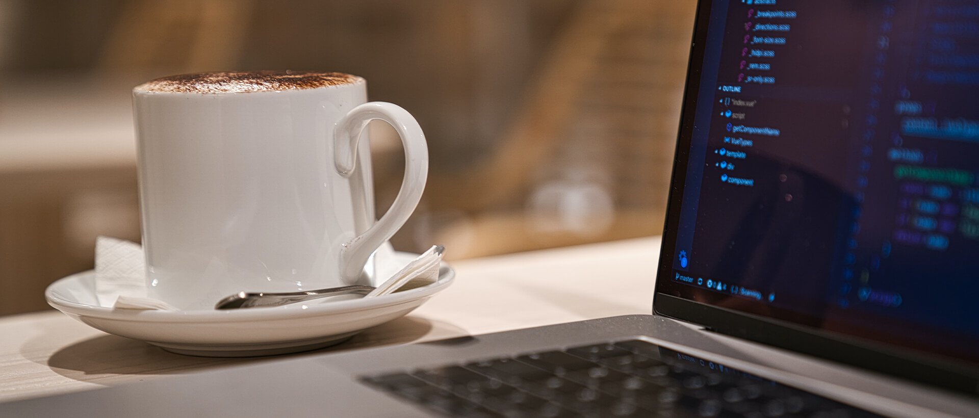 a cup of coffee sitting next to a laptop computer.