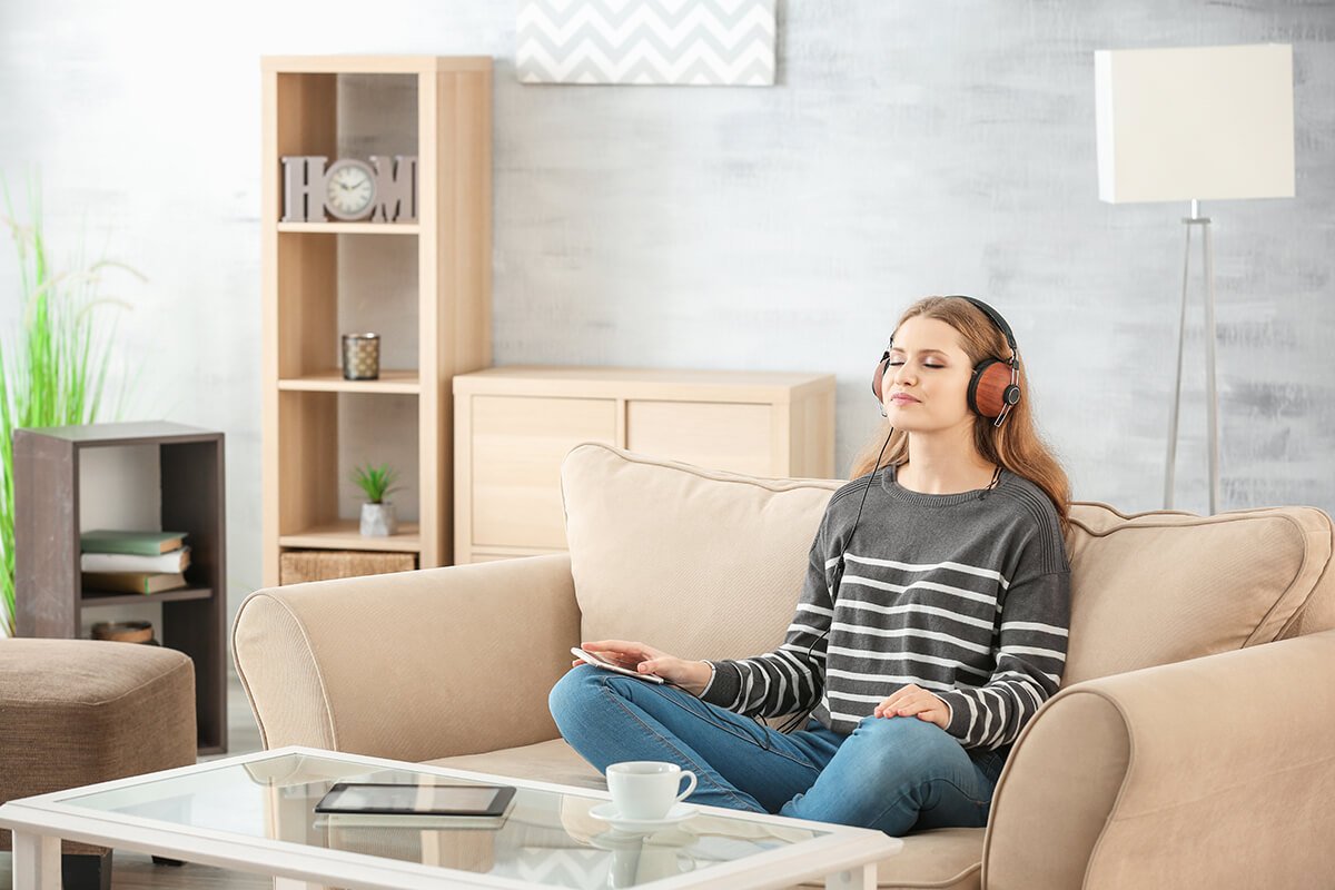 Woman sitting on couch practicing a guided meditation using an app
