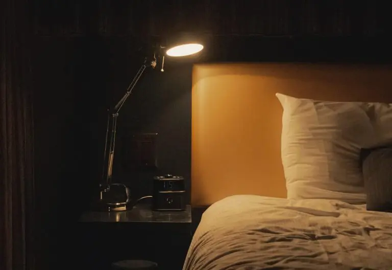 a bed with a white comforter and a night light.