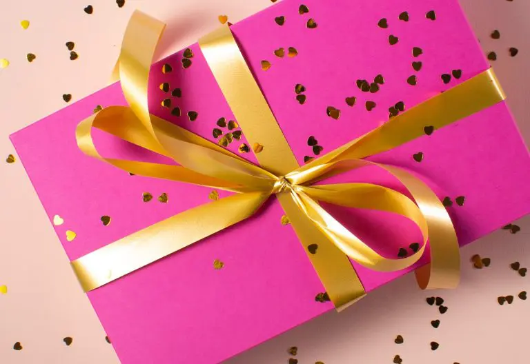a pink gift box with gold ribbon and confetti.
