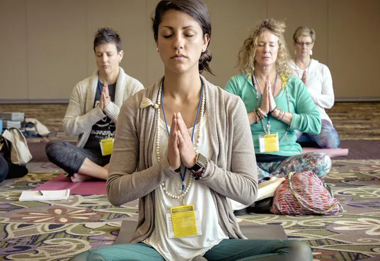 a group of women sitting in a circle doing yoga.