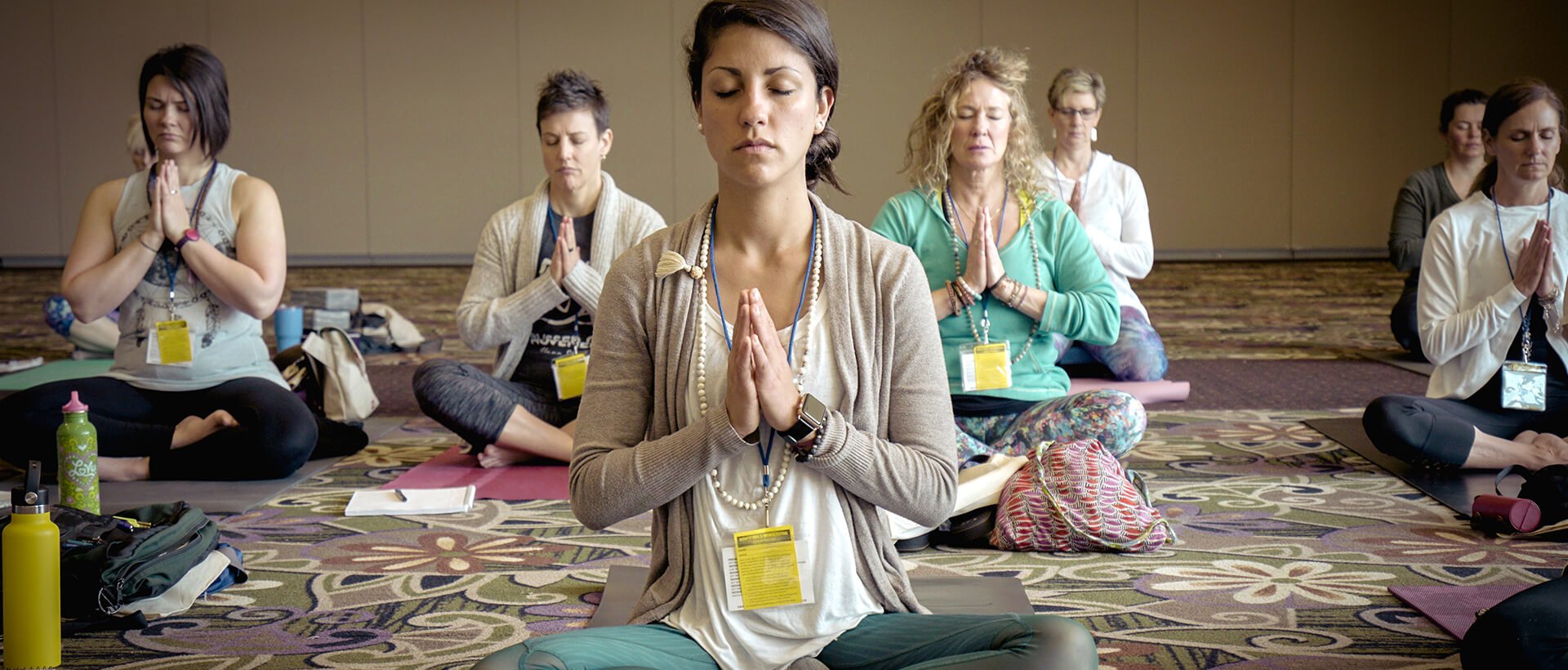 a group of women sitting in a circle doing yoga.