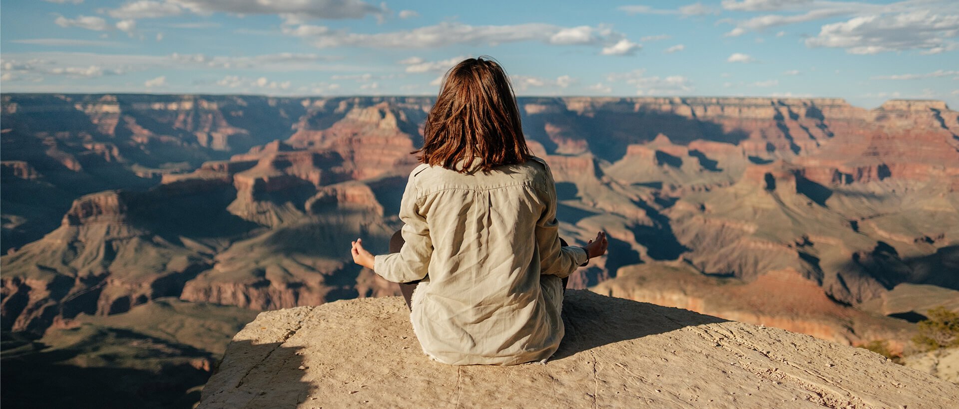 a woman sitting on top of a large cliff.