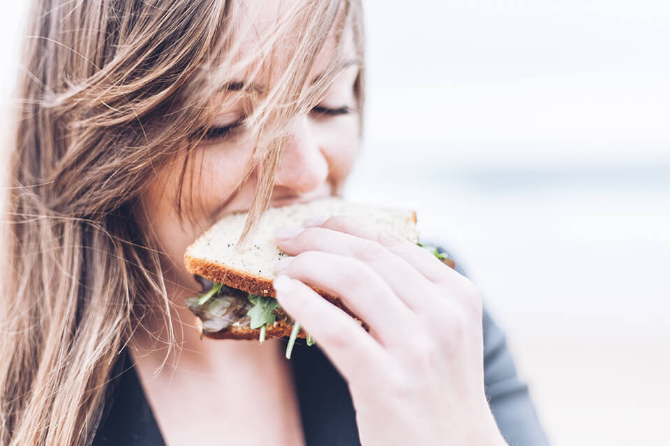Woman taking a big bite of a sandwich