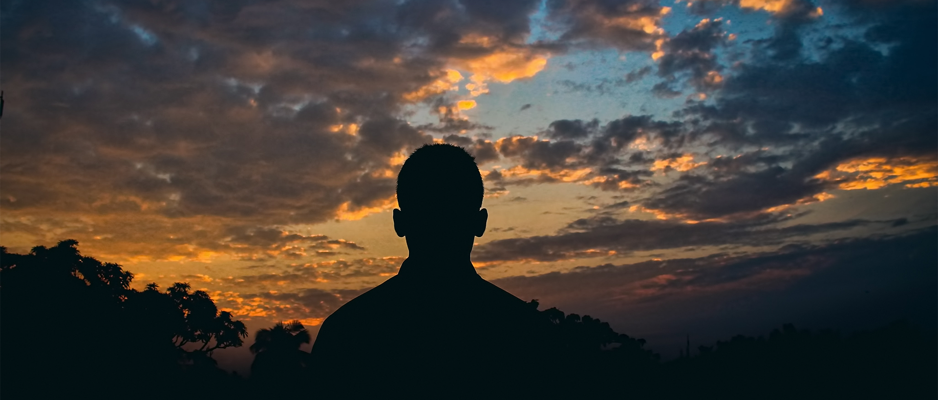 a silhouette of a man in front of a sunset.