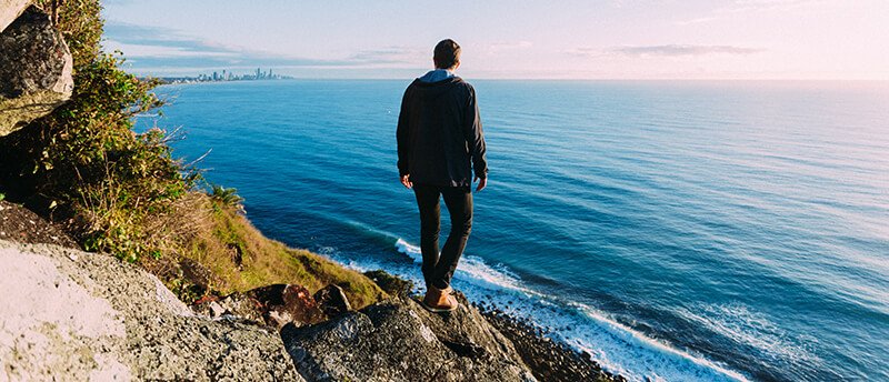 a man standing on a cliff overlooking the ocean.