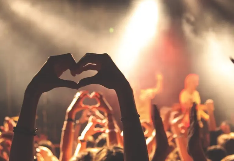 a crowd of people with their hands in the shape of a heart.