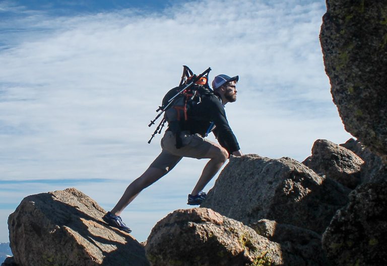 a man with a backpack climbing up a mountain.
