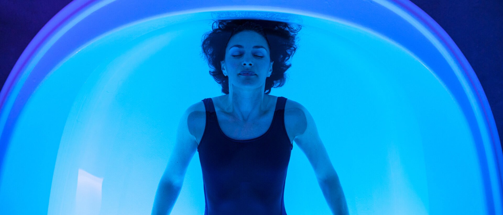 a woman in a black tank top floating in a blue tube.