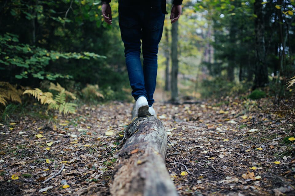 Man walking over log during hike in the great outdoors