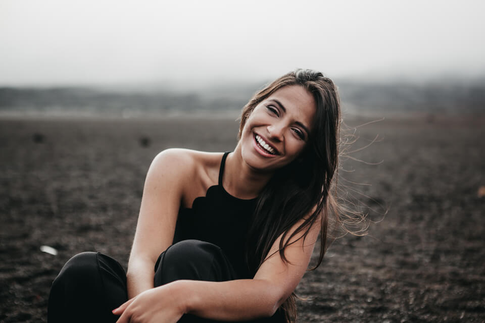 Woman sitting on ground smiling into camera