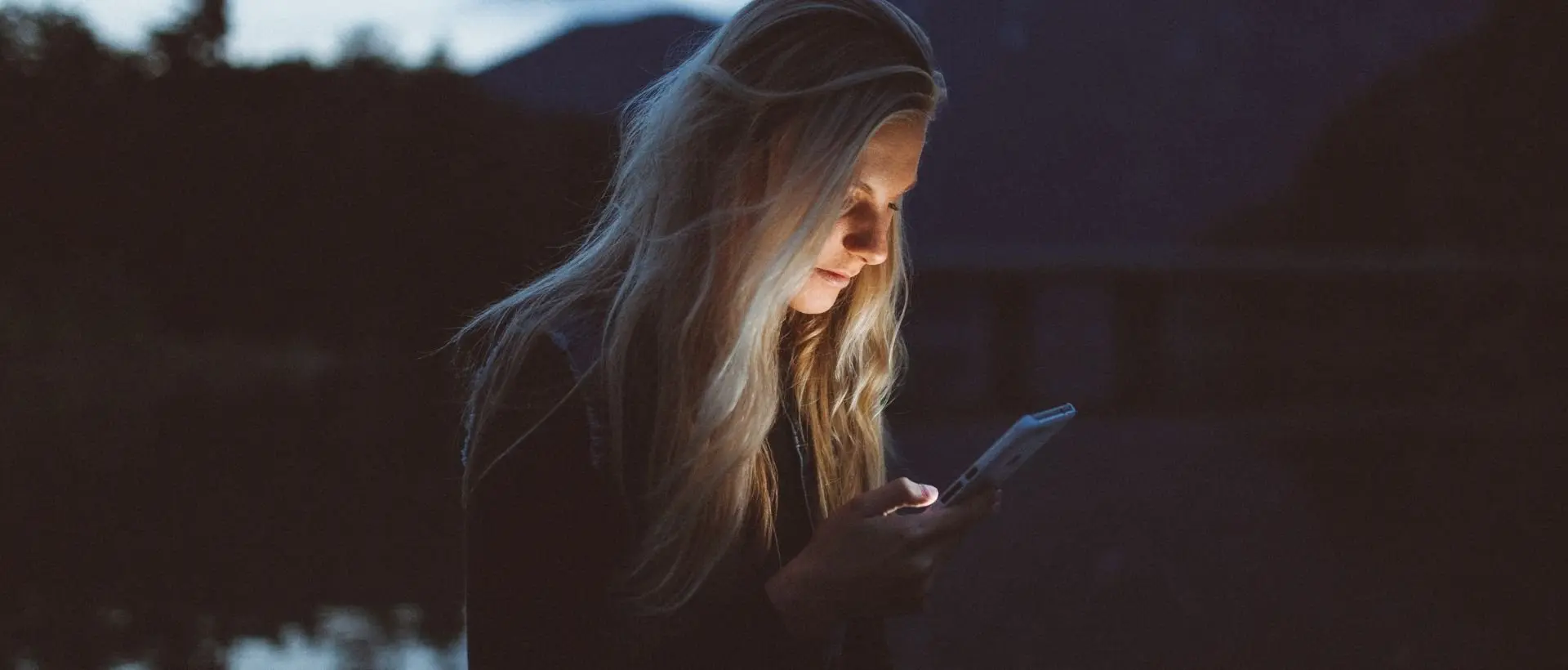 a woman looking at her cell phone in the dark.