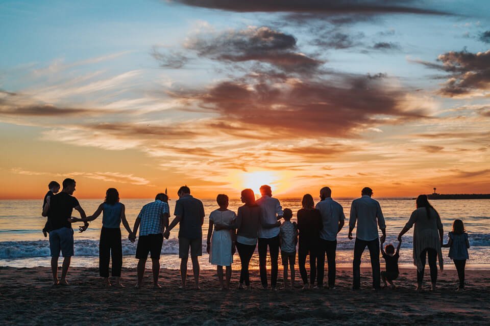 Group of friends and family standing together overlooking a sunset on the beach