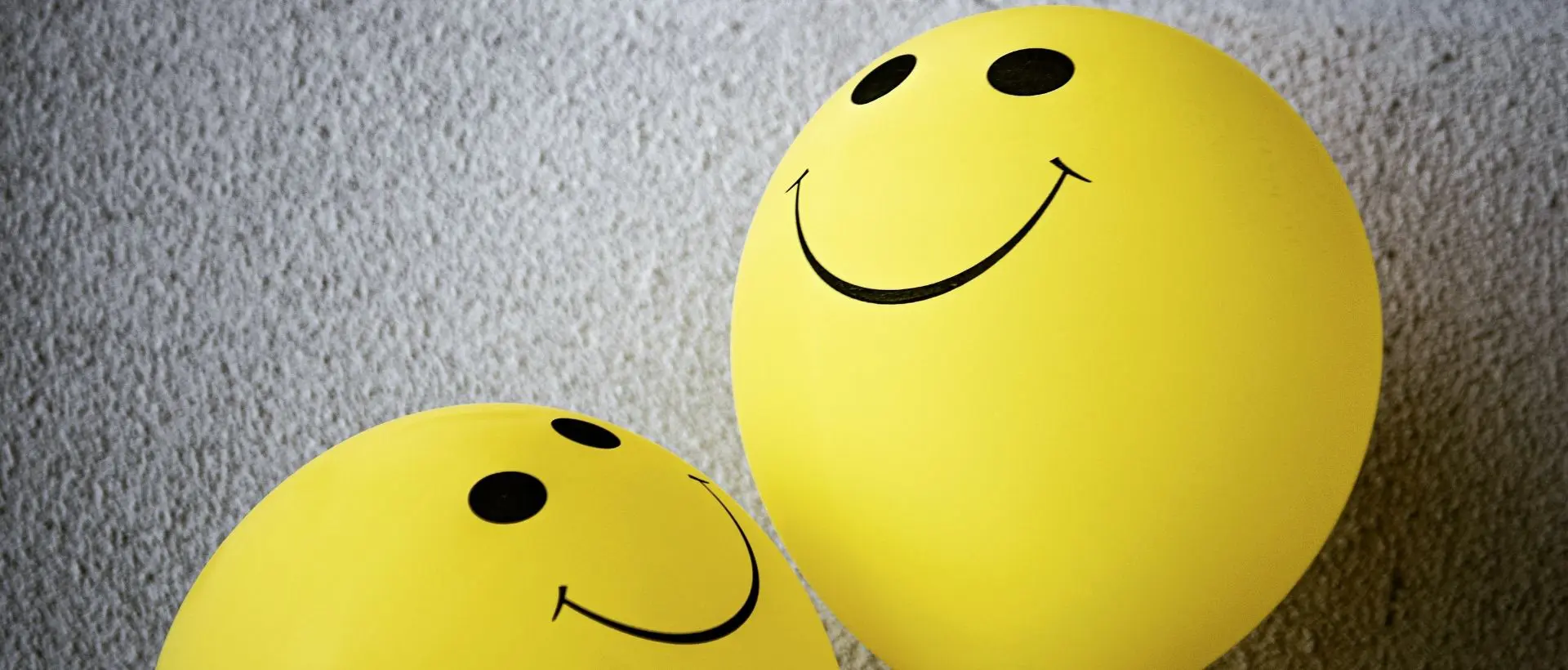 two yellow balloons with faces drawn on them.