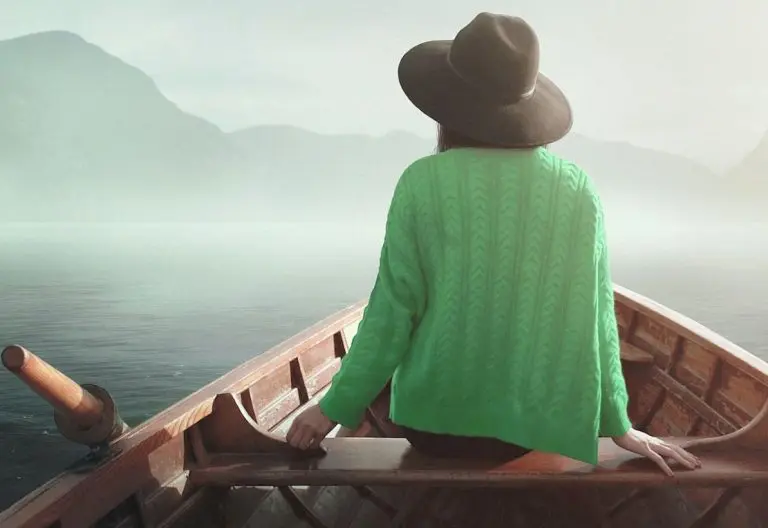 a woman in a green shirt is sitting in a boat.