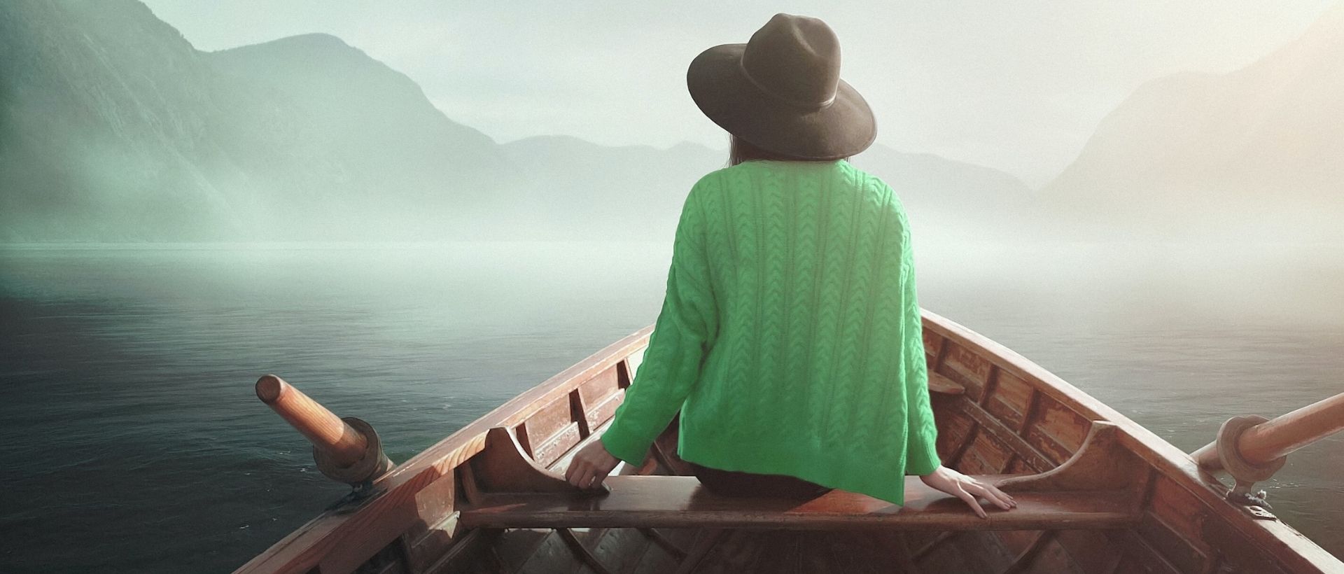 a woman in a green shirt is sitting in a boat.