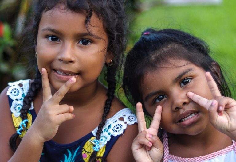 two little girls making peace signs with their hands.