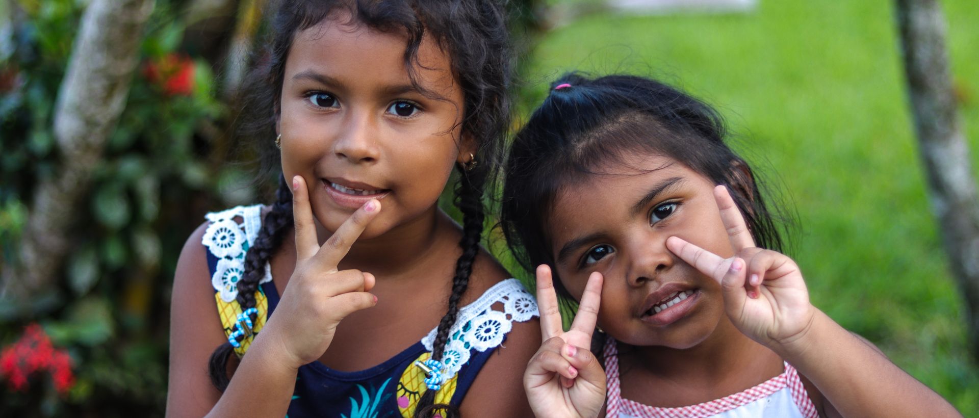 two little girls making peace signs with their hands.
