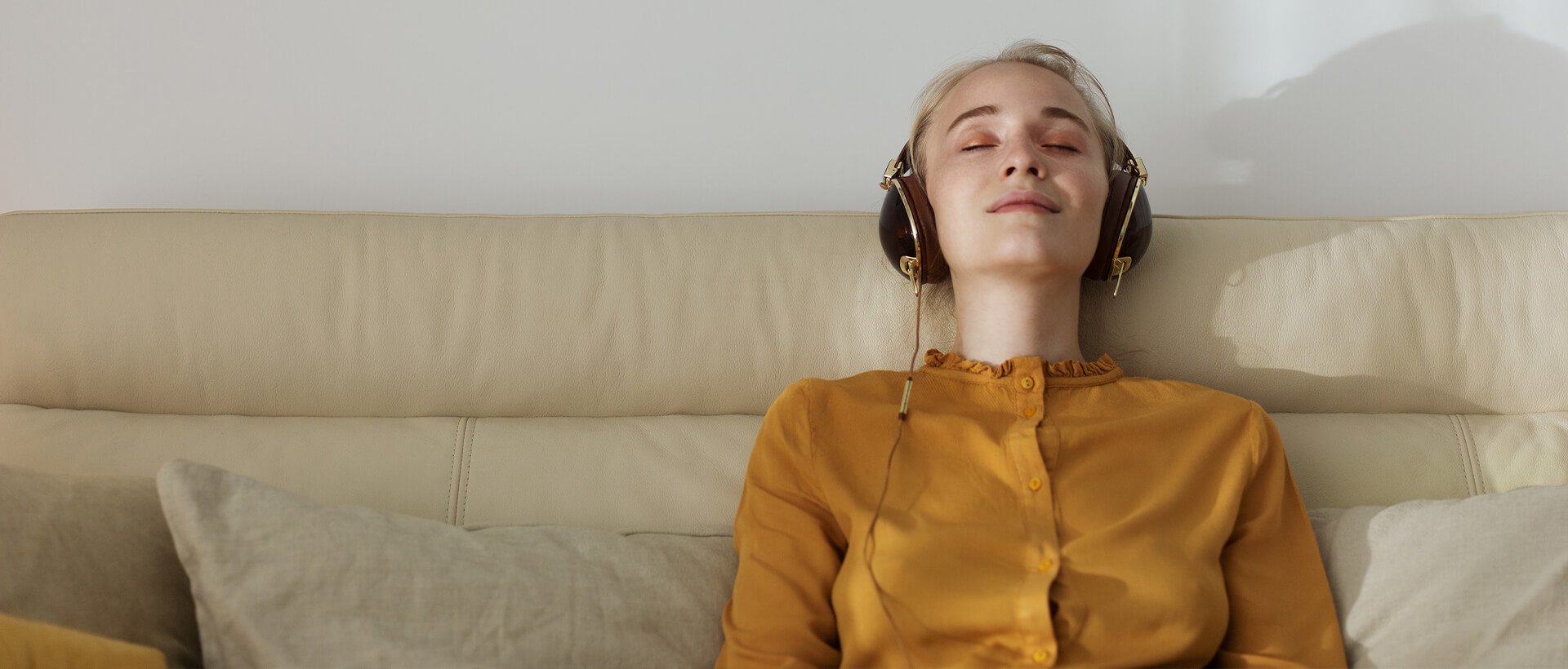 a woman wearing headphones laying on a couch.
