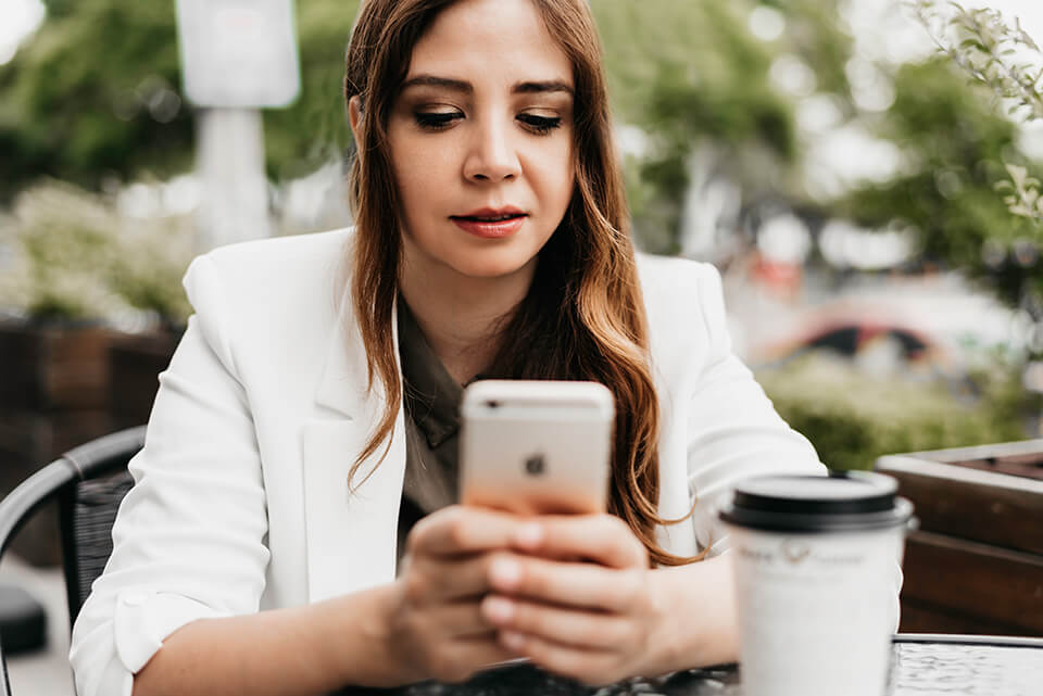Woman having coffee while doomscrolling on her phone