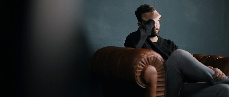 a man sitting on top of a brown couch.